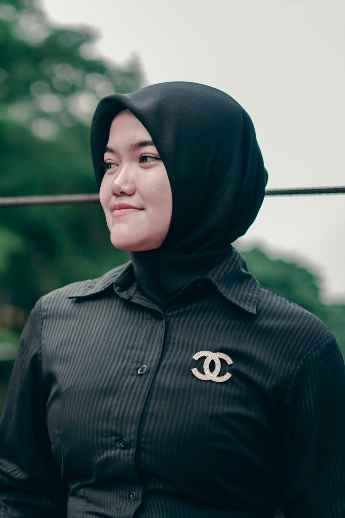 A woman wearing a black hijab and striped shirt.